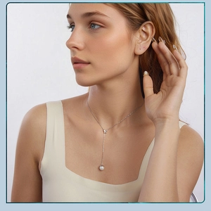 Silver Y-necklace with butterfly charm and dangling pearl drop worn by a model