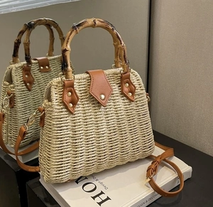 Detailed view of straw handbag with bamboo handle, leather flap and gold metal buckle