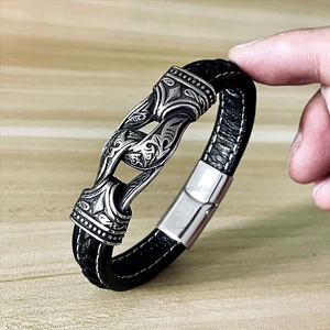 Macro detail of men's braided leather bracelet with vintage engraved metal charm