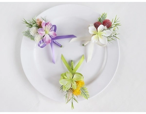 Detailed view of three artificial lily boutonnieres with silk ribbons and green leaves