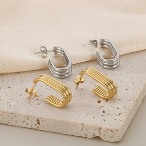 Macro detail of gold and silver C-shaped earrings with triple ribbed texture on stone
