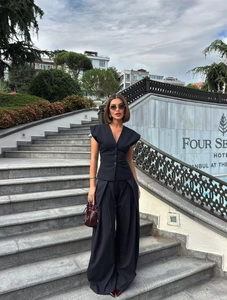 Detail view of navy striped vest and wide-leg trousers set in an outdoor fashion setting