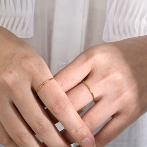 Minimalist gold stackable thin chain ring set worn by model on fabric background