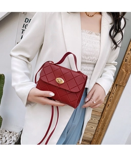 Detail of red quilted crossbody bag featuring gold twist lock and elegant top handle