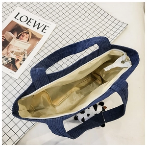 Close-up of dark blue corduroy handbag with smooth zipper closure and spacious beige lining