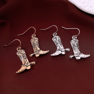 Detailed macro view of vintage western cowboy boot earrings in gold and silver finish