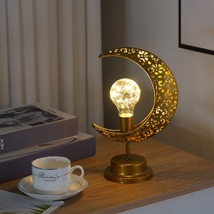 Détail de la lampe de table en métal doré en forme de lune avec motifs ajourés et LED