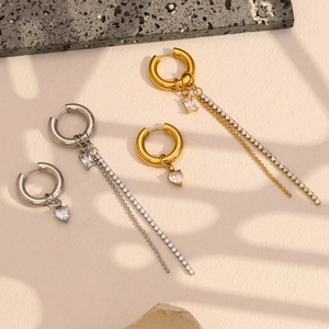 Detail of 18K gold plated asymmetric earrings with heart and tassel drop on stone