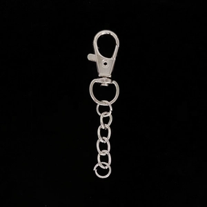 Detailed view of silver lobster claw clasp with metal chain links on black background
