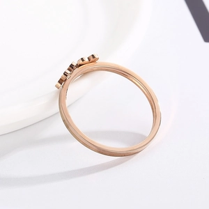Détail de la bague trèfle en or rose sur porcelaine avec motifs floraux polis