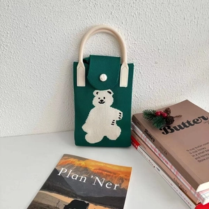 Detailed close-up of green knitted mini phone bag with cute white bear pattern and metal clasp