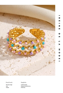 Detailed macro of golden triple-layer open ring featuring colorful enamel dot accents