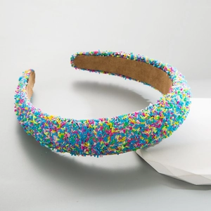 Fashionable wide headband with colorful sprinkle design on white geometric display stand