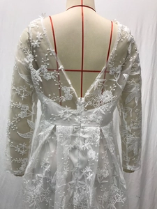Detail of bridal dress back featuring floral lace embroidery and sheer mesh long sleeves