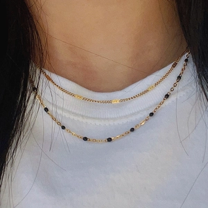 Minimalist double-layer gold chain necklace with black beads on a model's neck