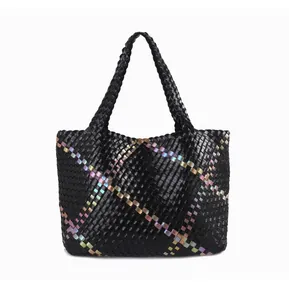 Detail of multi-color woven tote bag with glossy synthetic leather texture and handles