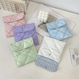 Flat lay of quilted mini storage pouches in pastel colors with heart buttons and soft textures