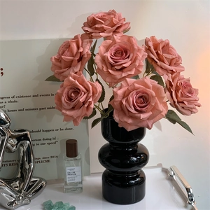 Detailed close-up of realistic pink artificial roses in a black vase for home decor