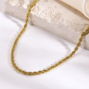 Detail of a gold plated stainless steel twist rope chain necklace on soft silk fabric