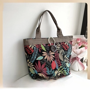 Detail view of printed linen tote bag with wooden button closure and maple leaf pattern