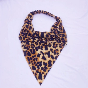 Detail of leopard print triangle headscarf with elastic band on white fabric background