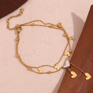 Close-up of golden double-layered heart anklet with white shell heart and round beads