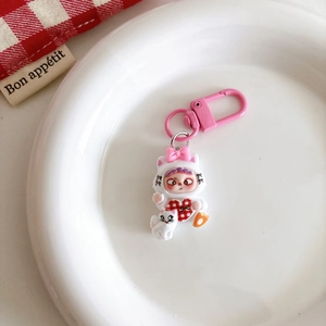 Close-up of cute cartoon girl keychain in cat costume with pink hook on white plate