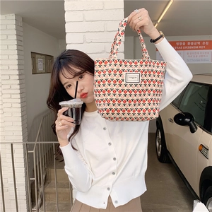 Close-up of corduroy tote bag featuring red tulip patterns and Pleasant Time label