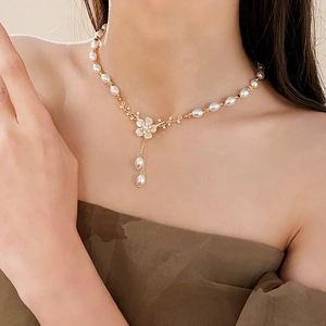 Détail d'un collier floral doré avec zircon, pétales de nacre et glands de perles
