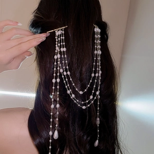Elegant gold hair clip with long pearl tassels and drop-shaped pearls on dark hair