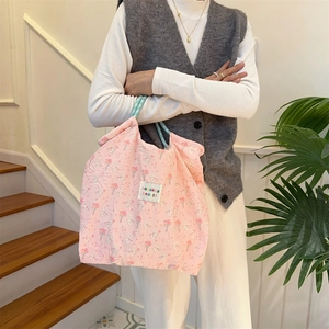Detailed shot of pink canvas tote featuring bunny print and green handle on indoor stairs