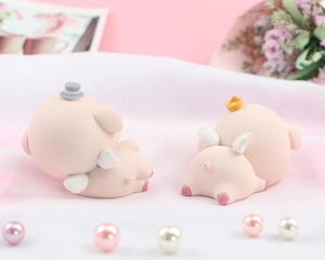 Rear view of two cute pink resin pig ornaments with crown and hat for cake decoration