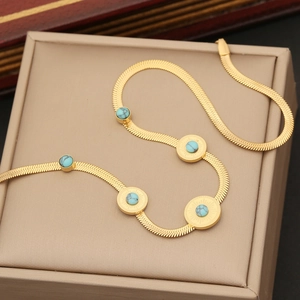 Golden stainless steel flat snake chain necklace with turquoise gemstones on jewelry box
