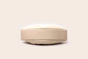 Detailed bottom view of a beige ruched cloud bag showing premium leather texture and shape