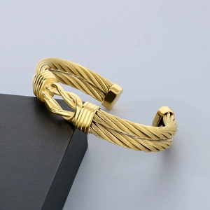 Detailed view of golden stainless steel cable twist bracelet on a black display box