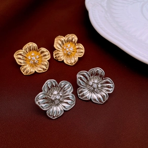Close-up of gold and silver flower stud earrings with zirconia on red velvet
