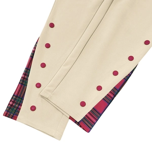 Dettaglio dei pantaloni beige con patchwork scozzese rosso e verde e bottoni rossi