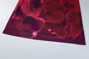 Détail du tissu en mesh respirant avec imprimé floral rouge foncé et couture fine sur l'ourlet
