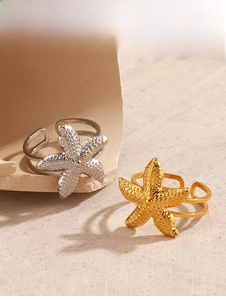 Detailed close-up of gold and silver starfish open rings on textured beige surface