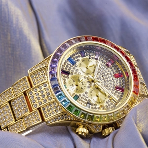 Macro shot of gold-plated iced-out chronograph watch with rainbow crystal bezel on fabric