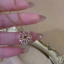 Macro detail of a gold heart-shaped four-leaf clover necklace with sparkling white zircons
