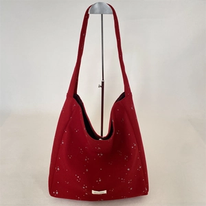 Dettaglio borsa tote in lana rossa con stelle argentate ed etichetta del marchio