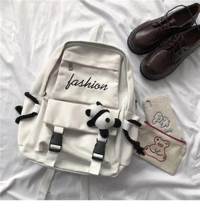 Detail of off-white canvas backpack with black buckles, panda charm and fashion embroidery