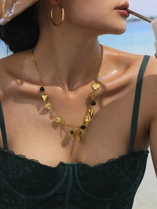 Detail of 18k gold plated ferris wheel heart necklace and hoop earrings on model