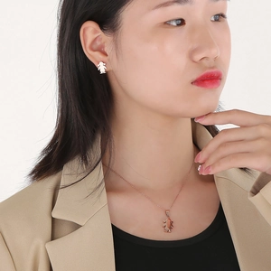 Detailed view of rose gold cartoon girl pendant necklace and silver earrings set on model
