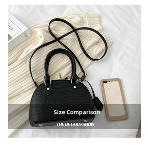 Detailed top view of black croc-effect shell bag with metal rivets and shoulder strap