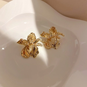 Detailed view of vintage gold flower earrings with embossed texture on white display
