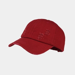 Macro detail of deep red washed cotton baseball cap with vintage distressed holes