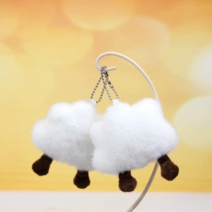 Close-up of white fluffy sheep plush keychain with brown legs on a metal display stand