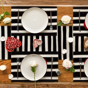 Close-up of black and white striped linen placemats and runner on a wooden dining table